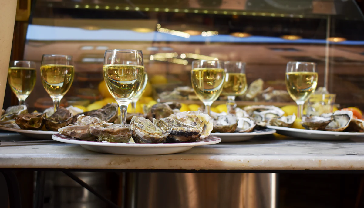 A platter of fresh oysters on ice beside glasses of chilled Oregon white wine