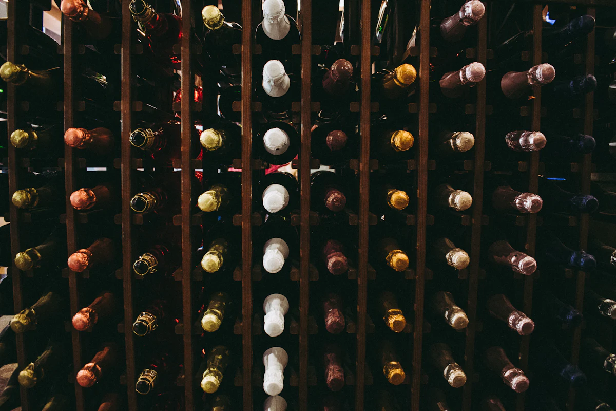 Wine bottles resting on their sides in a wooden home cellar rack