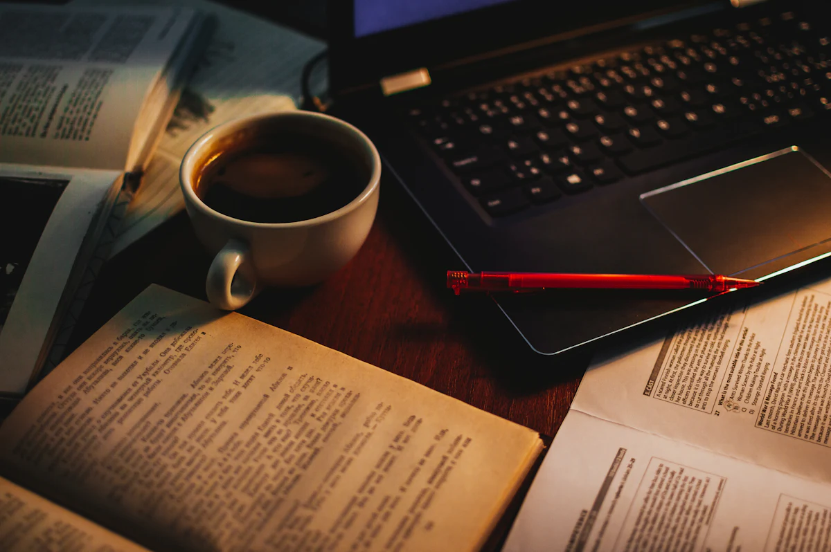 A writer’s desk with a notebook, laptop and glass of wine ready for drafting copy